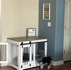 a small dog standing next to a wooden crate with two dogs in it's kennels