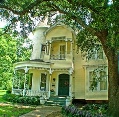 a large yellow house sitting next to a tree