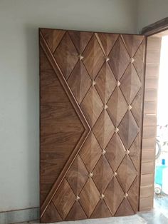 a large wooden door in the corner of a room with white walls and tile flooring