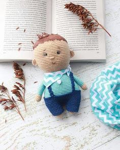 a crocheted doll sitting on top of an open book next to some dried plants