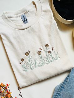 An embroidered daisies and bees design embroidered on a Ultimate Cotton Gildan/ Comfort Colors Crewneck Tee Fall Cotton T-shirt With Floral Embroidery, Casual Daisy Print T-shirt With Crew Neck, Daisies And Bees, Cheap Cotton T-shirt With Daisy Print, Spring Daisy Print Graphic Tee, Bees Design, Embroidered Daisies, White Cotton T-shirt With Daisy Print, Spring Daisy Print Relaxed Fit T-shirt