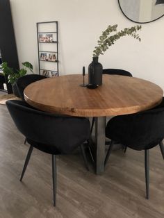 a round wooden table with black chairs around it