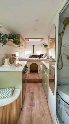 the inside of a camper with wood floors and green walls, white counter tops, and wooden flooring