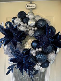 a wreath with blue and silver decorations hanging on the front door