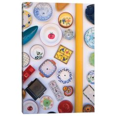 many different plates and bowls are arranged on a white surface with a yellow pole in the foreground