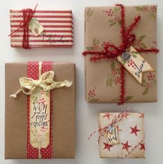 presents wrapped in brown paper and tied with red ribbon are sitting on a white surface