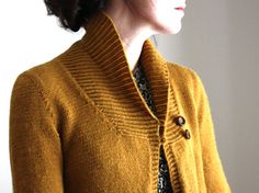 a woman is wearing a yellow cardigan sweater