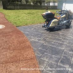 a motorcycle parked on the side of a road next to a driveway with grass in the background