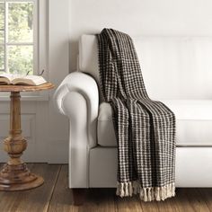 a white couch with a black and white checkered blanket on it next to a window