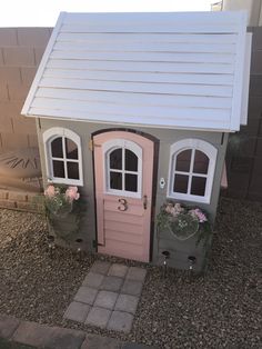 a pink and gray doll house with two windows on the front, one door is open