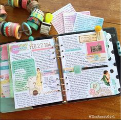 an open planner book sitting on top of a wooden table next to spools of thread