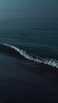 a person riding a surfboard on top of a wave in the ocean at night