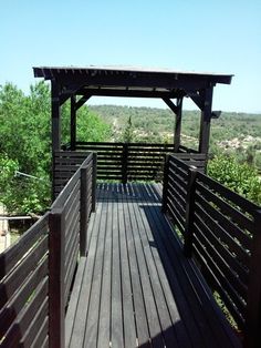 a wooden deck with a gazebo on top of it and trees in the background