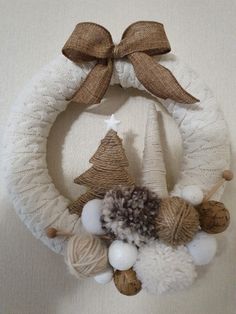 a knitted wreath with white balls and brown ribbon hanging from the front of it