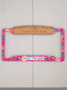 a license plate frame with the words enjoy the ride printed on it and a cork holder