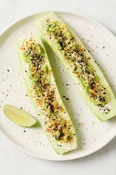 two slices of zucchini on a white plate with seasoning sprinkles