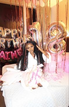 a woman sitting on top of a bed next to balloons