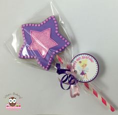 two decorated cookies in cellophane bags on top of a white table with pink and purple decorations