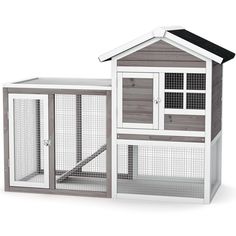 a white and gray chicken coop with an open door on the side, next to it's roof