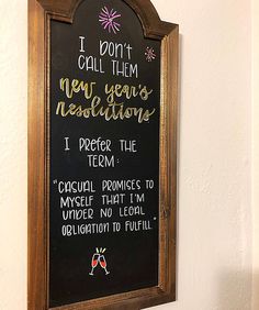 a chalkboard sign hanging on the wall next to a white wall with writing in it