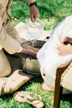 a person pouring water into a pot on the grass