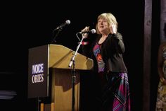 a woman standing at a podium speaking into a microphone