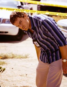 a man standing in front of police tape with his hand on the ground and looking at something