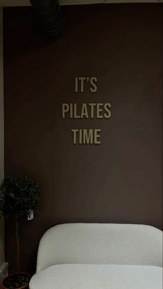 there is a white bed in front of a brown wall with it's pilates time written on it