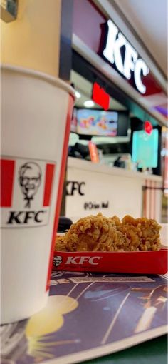 a close up of a tray of food next to a cup of kfc coffee