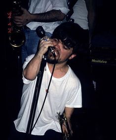 a man singing into a microphone while standing next to other people