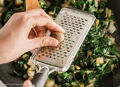 someone grating vegetables in a skillet with a wooden spoon