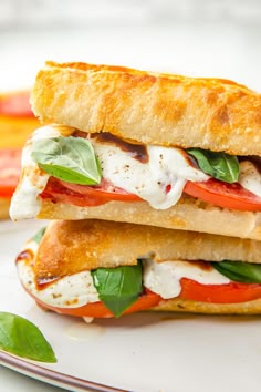 two sandwiches stacked on top of each other with cheese and tomato slices in the middle