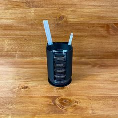 a glass with two straws in it sitting on a wooden table