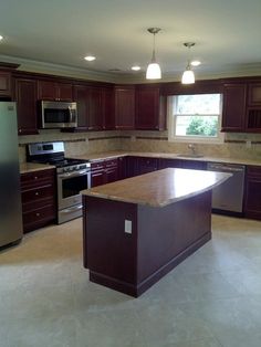 a large kitchen with an island in the middle and stainless steel appliances on both sides