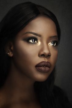 a woman with long black hair and gold eyeshadow is looking at the camera