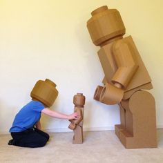 a person kneeling down next to a cardboard sculpture