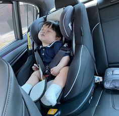 a young boy sleeping in the back seat of a car, with his head propped up