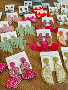 several pairs of earrings are displayed on a table with cards and other items in front of them