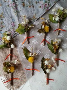 small bouquets of dried flowers are arranged on a lace tablecloth with twine