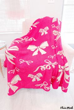 a pink blanket sitting on top of a white chair