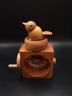 a wooden toy bird sitting on top of a piece of wood