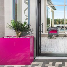 a pink planter sitting in front of a large glass door to a living room