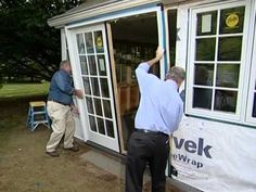 two men are painting the outside of a house with windows and sidings on it