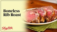 a white plate topped with sliced meat on top of a wooden table next to green napkins