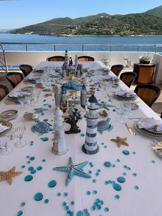 the table is set with blue and white plates, silverware and starfish decorations