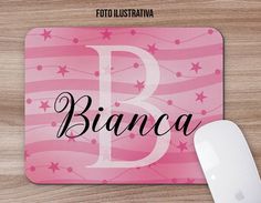 a pink mouse pad with the letter b in black ink and stars on it, next to a computer mouse