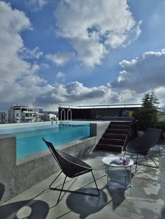 an outdoor patio with chairs, tables and a swimming pool on the roof top terrace