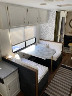 the interior of a recreational vehicle with white cabinets and black counter tops, including a bed