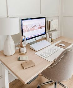 a desk with a computer, keyboard and mouse on it in front of a lamp