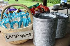 a basket full of camping gear sitting on top of a table next to two tin cans